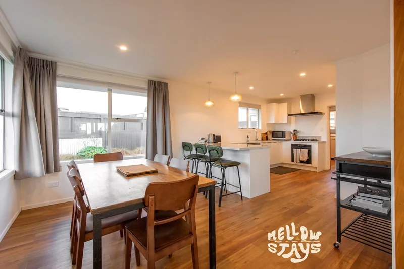 Salt House kitchen and dining area with a wooden table and green breakfast-bar stools